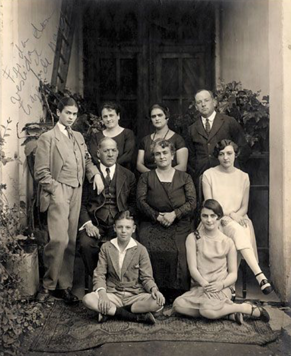 black and white family portrait of the Kahlo y Calderon family with Frida Kahlo far left dressed in men's three piece suit 