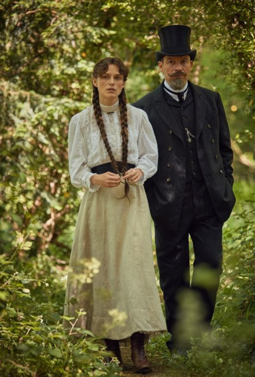 Keira Knightley as Colette and Dominic West as Willy walk in the woods together in Colette